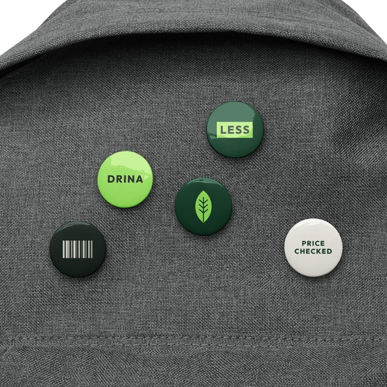 Five Drina pin buttons on a grey backpack
